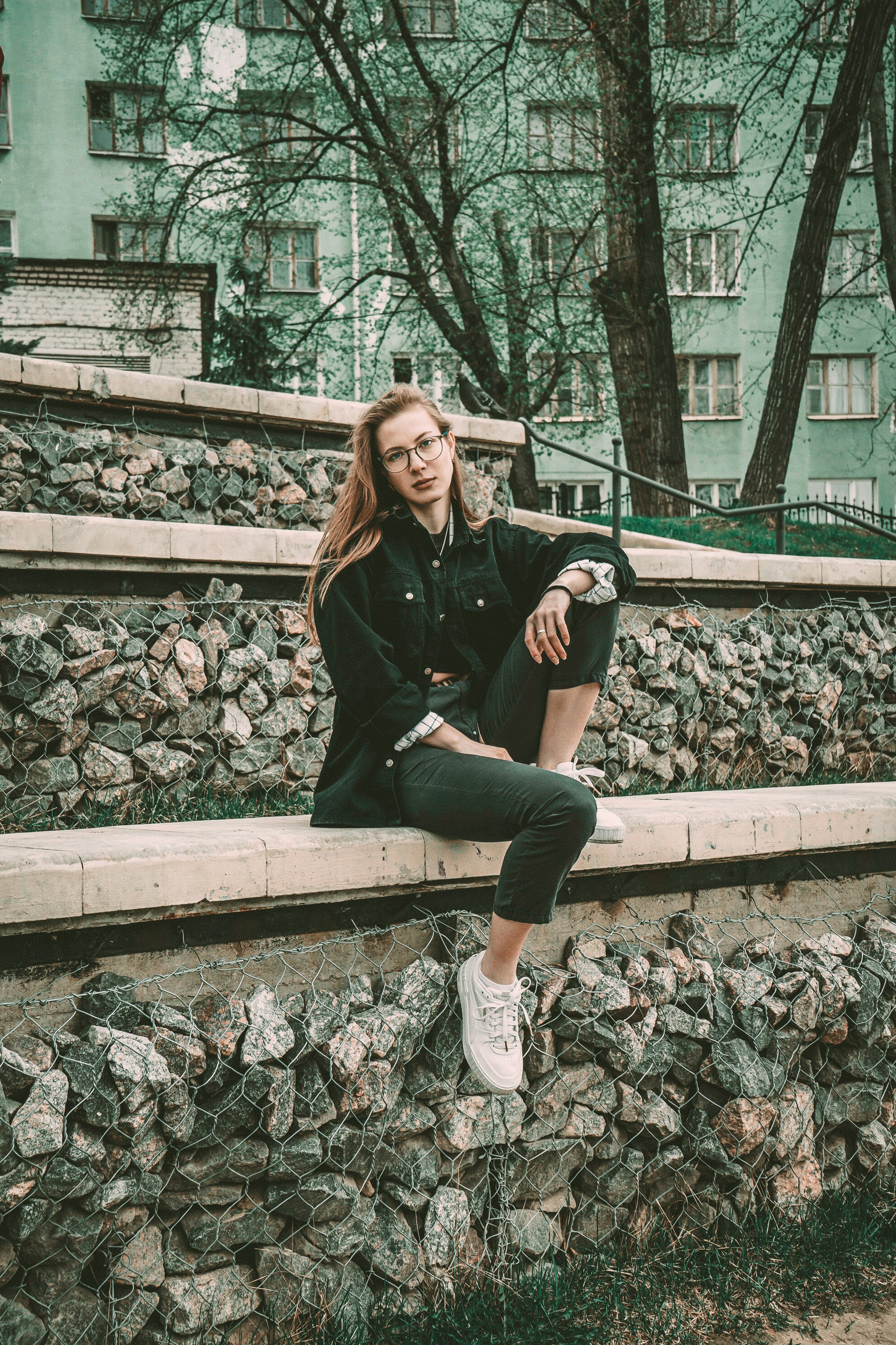 woman in black leather jacket sitting on concrete stairs